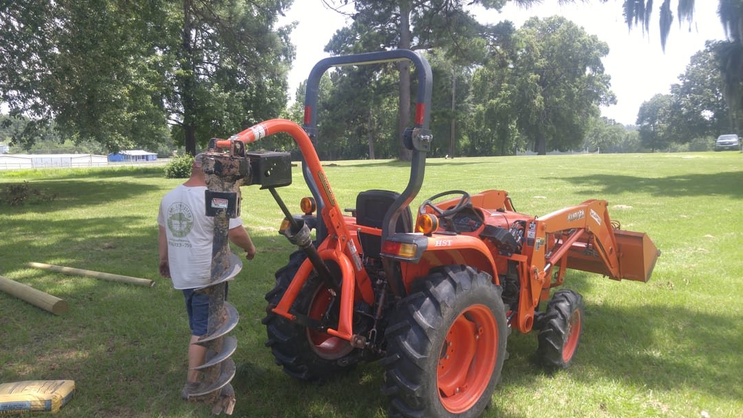 Tractor-mounted auger drilling post holes