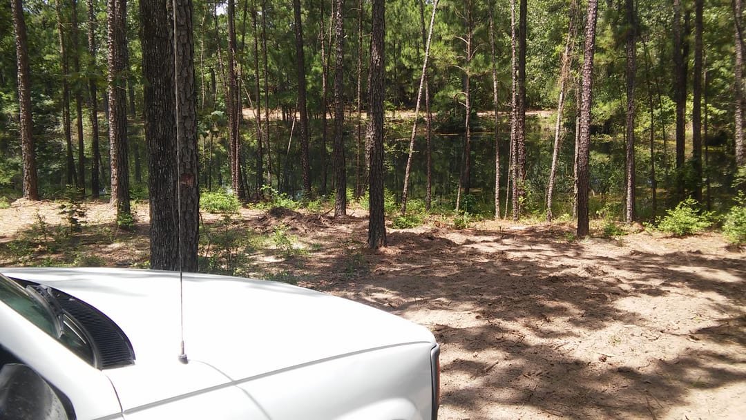 Overview of a lake-area property with outbuildings and fence