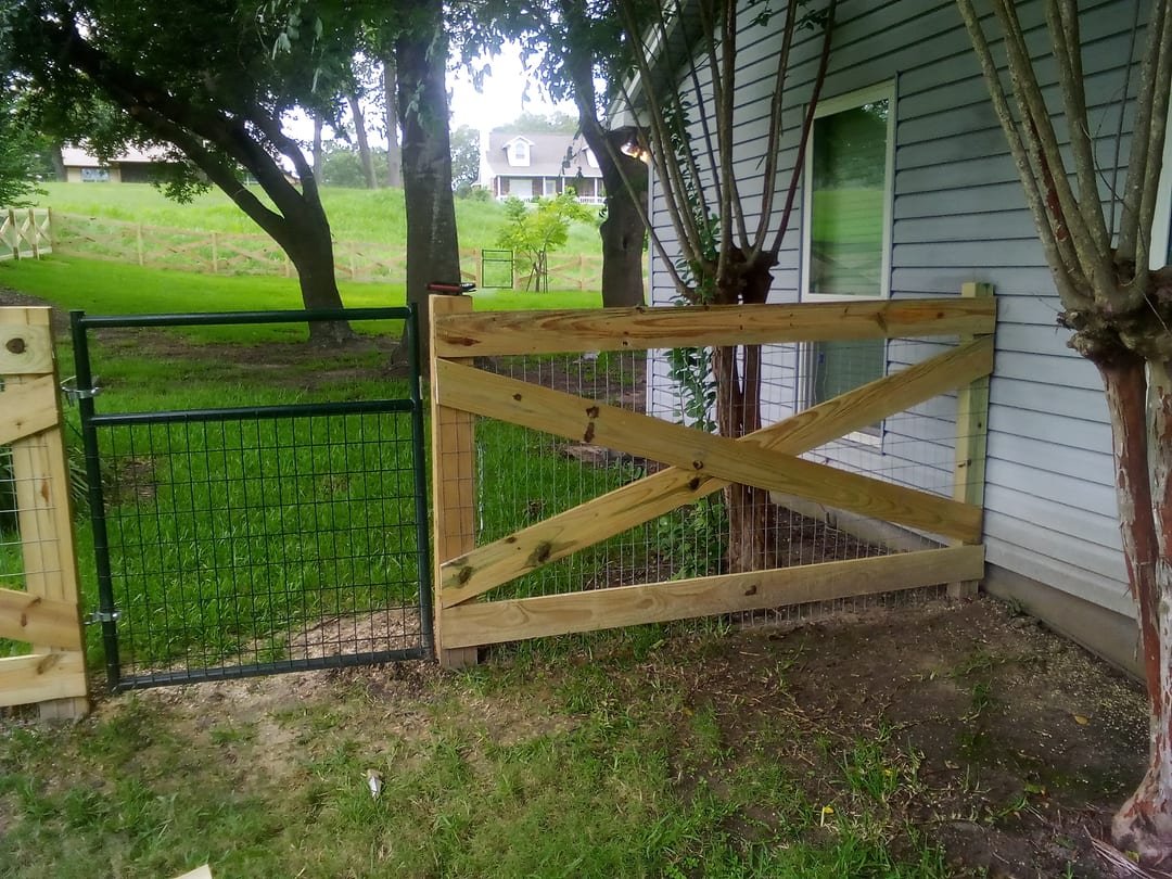 Cross buck fence with a matching gate near a house on acreage