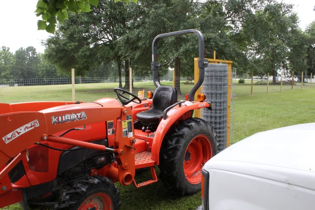 Woven wire field fence being built along a cleared line