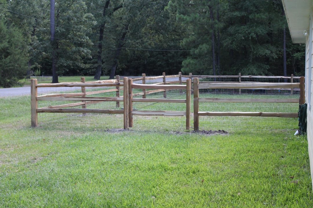 Split rail fence with wire backing and a gate at a driveway