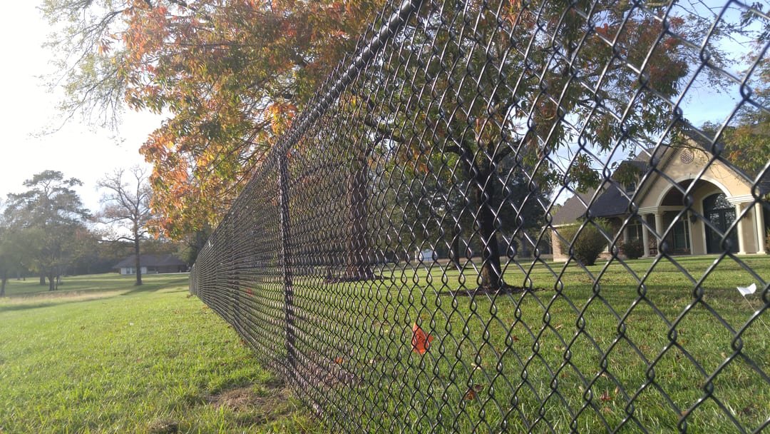 Black vinyl-coated chain link fence along a large estate lot