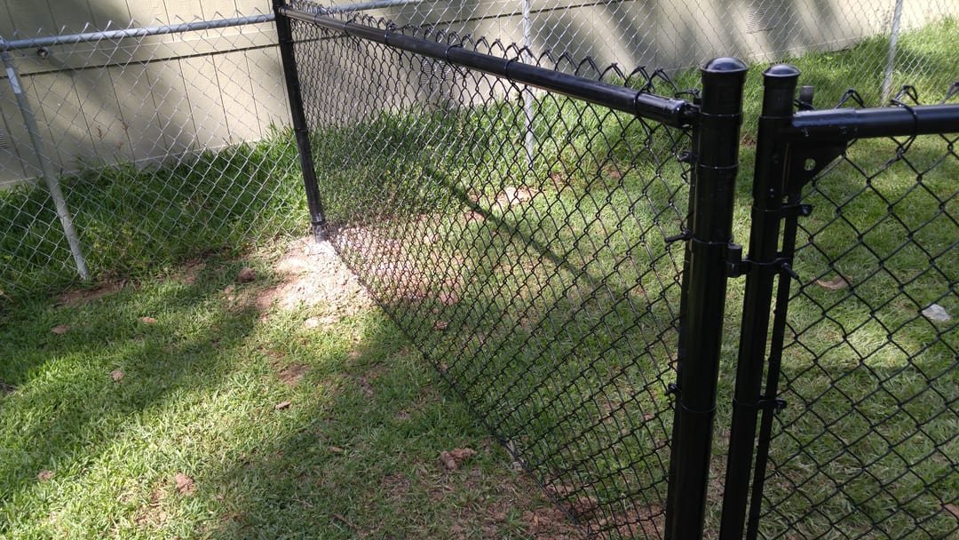 Black metal gate at a driveway with fencing on either side