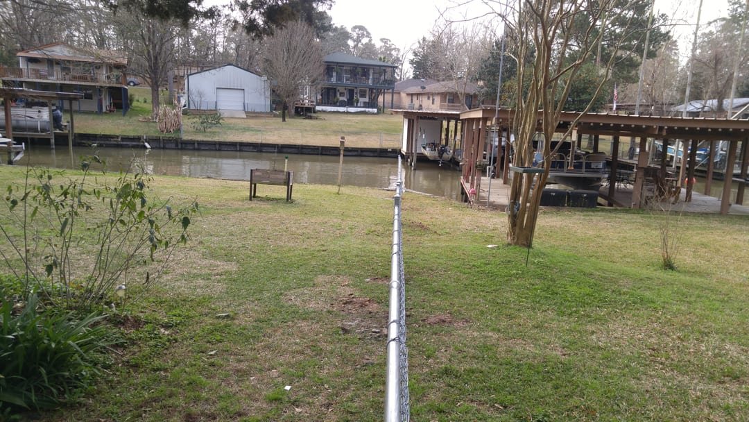Fence line running down a sloped lot toward Lake Livingston