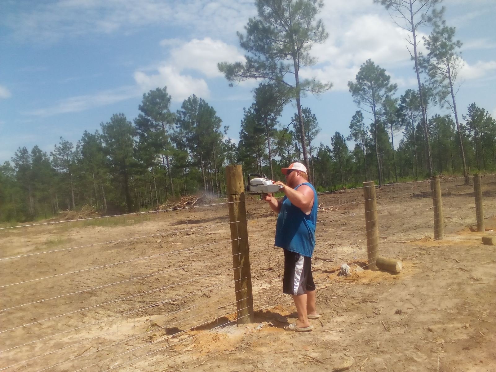 Worker setting a field fence post