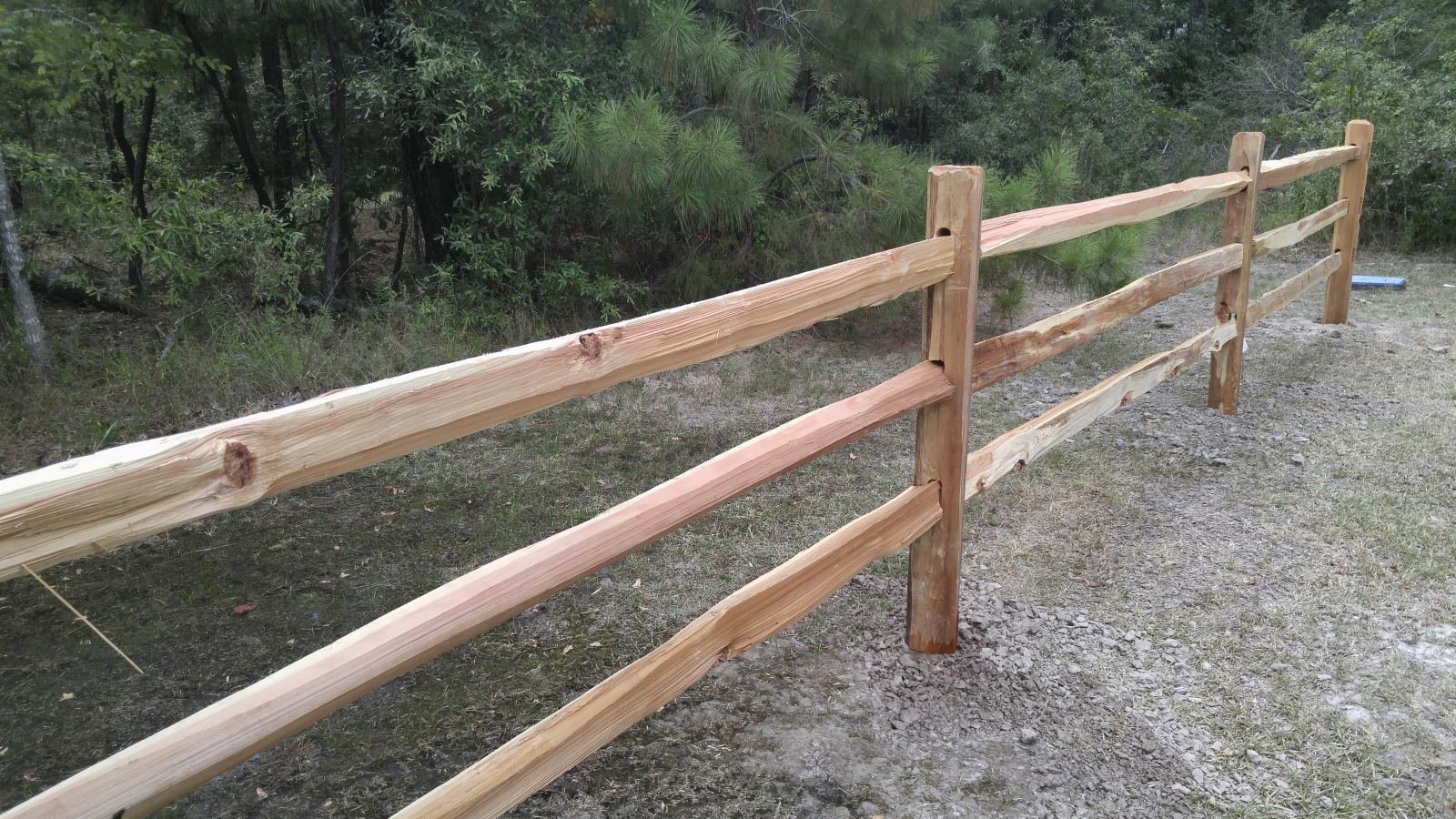 Finished cedar split-rail fence through a wooded property