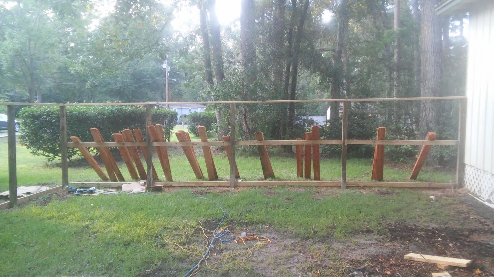 Wood privacy fence frame under construction with boards drying