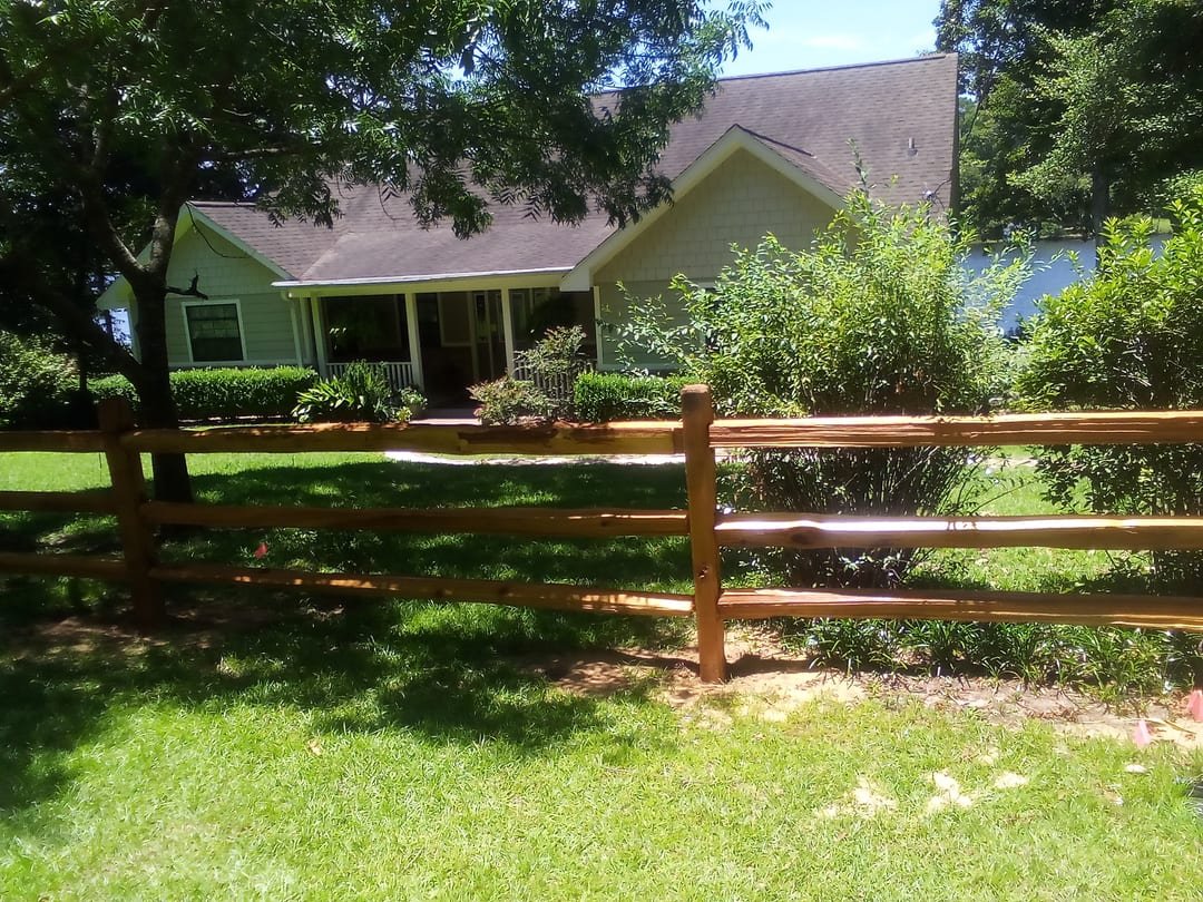 Cedar split rail fence in front of a lake house