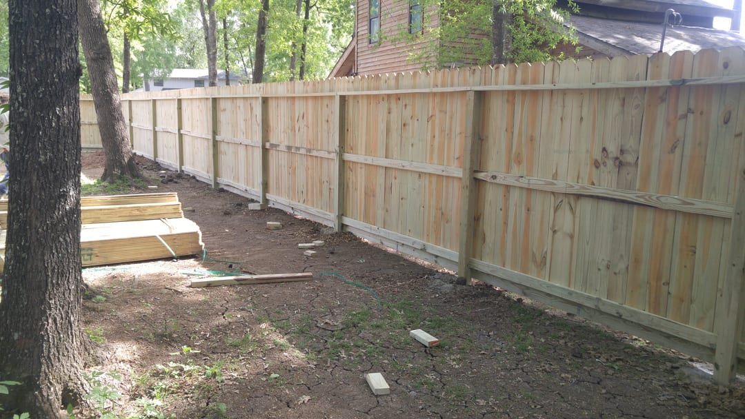 Tall cedar privacy fence enclosing a backyard, freshly built
